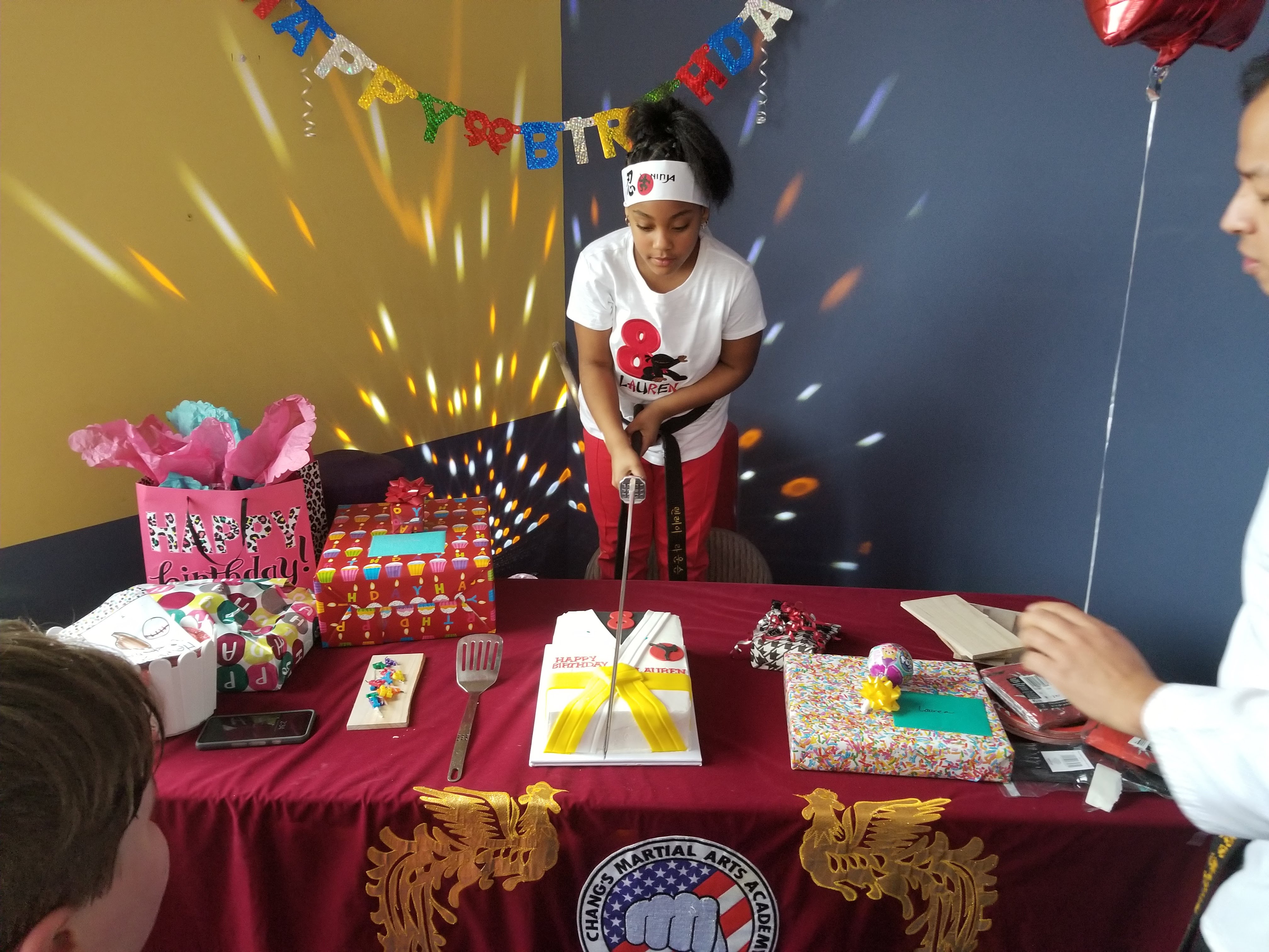 Birthday cake being cut with a Samurai sword during an Attack Taekwondo birthday party